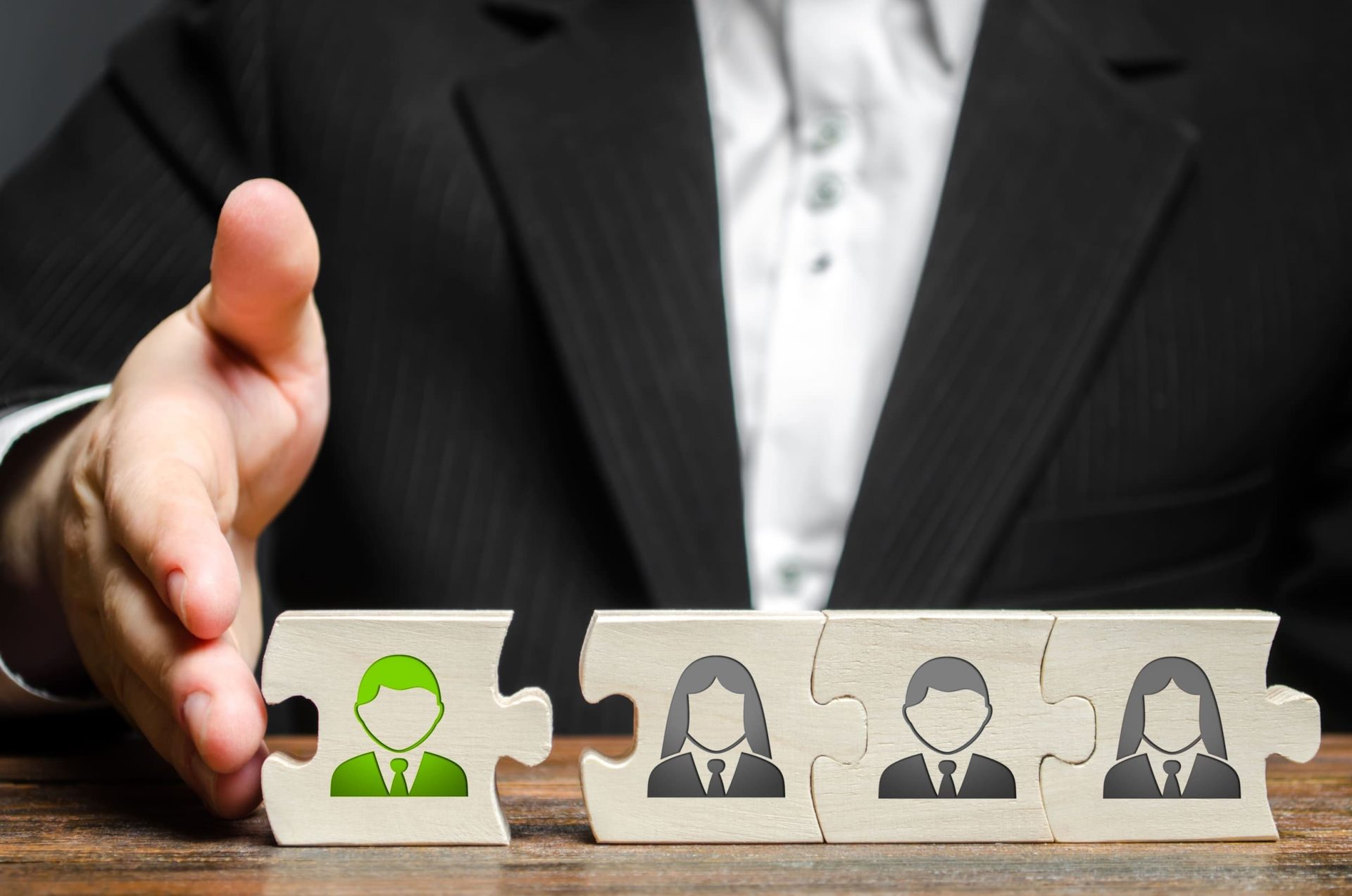 miembro familiar destacado en verde junto a otras tres figuras en gris, representando la integración y el acuerdo entre los miembros de una empresa familiar a través de un protocolo familiar.