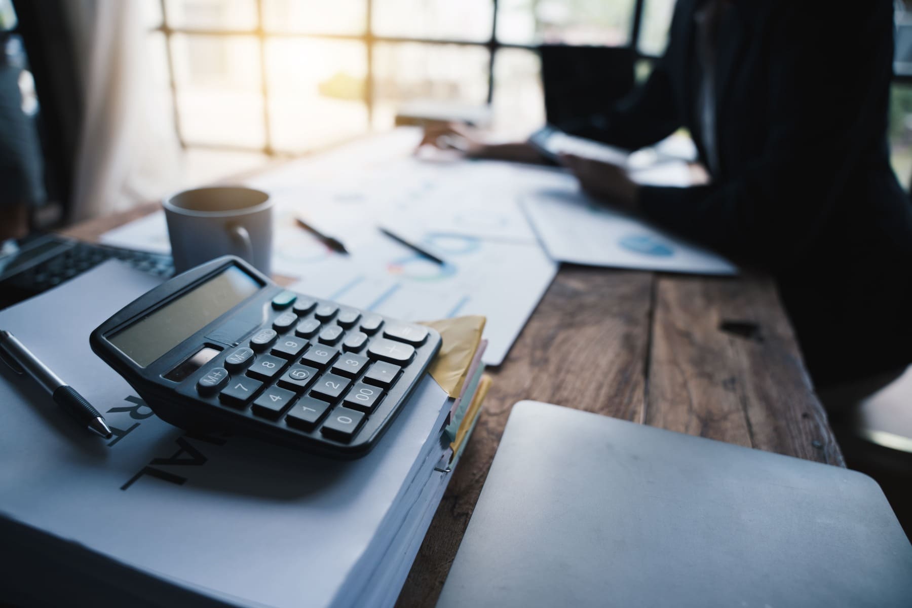 Calculadora y documentos financieros sobre escritorio de trabajo, representando el cálculo de la base de cotización de autónomos societarios en 2026.
