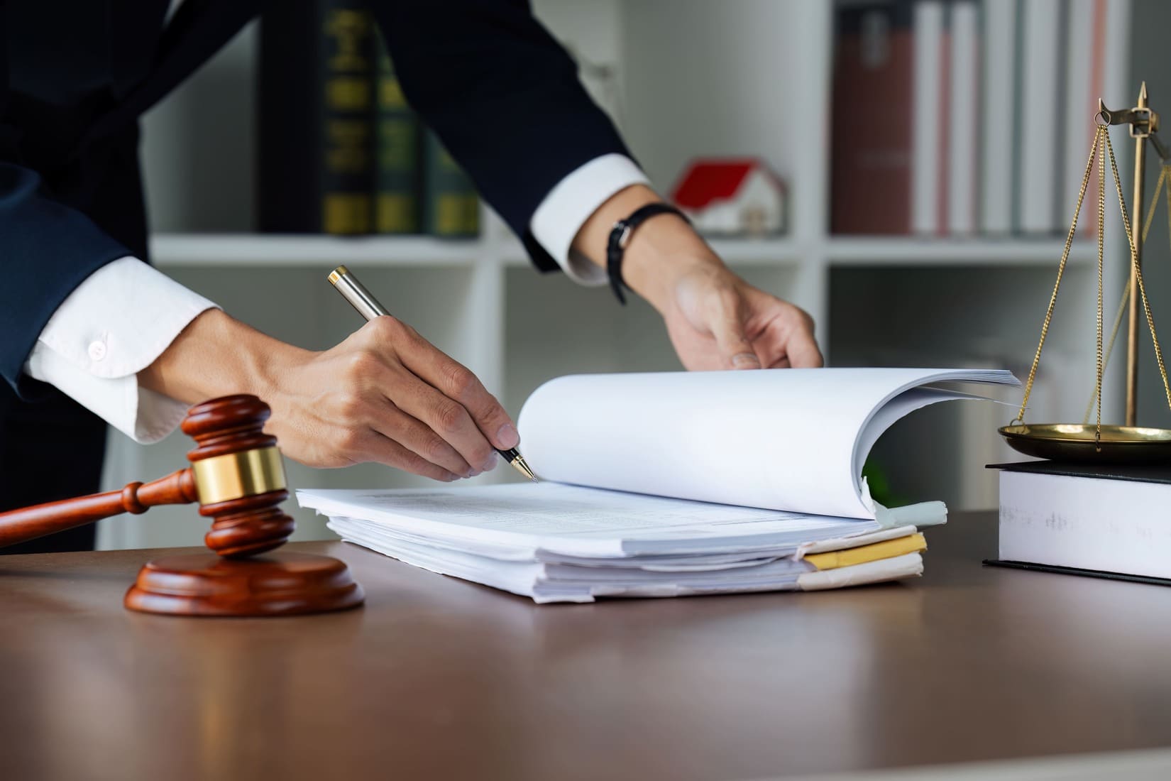 Abogado revisando documentos legales junto a mazo judicial y balanza de la justicia, representando el procedimiento penal en delitos societarios.