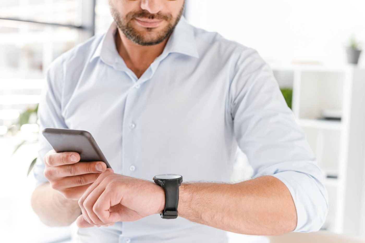Profesional comprobando la hora en el reloj mientras registra su jornada laboral desde el móvil, representando el fichaje digital obligatorio en empresas.