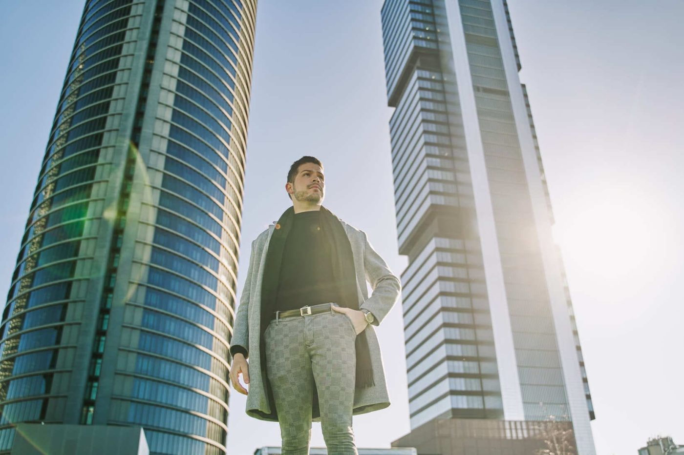Empresario de pie entre dos torres de oficinas en un distrito financiero.